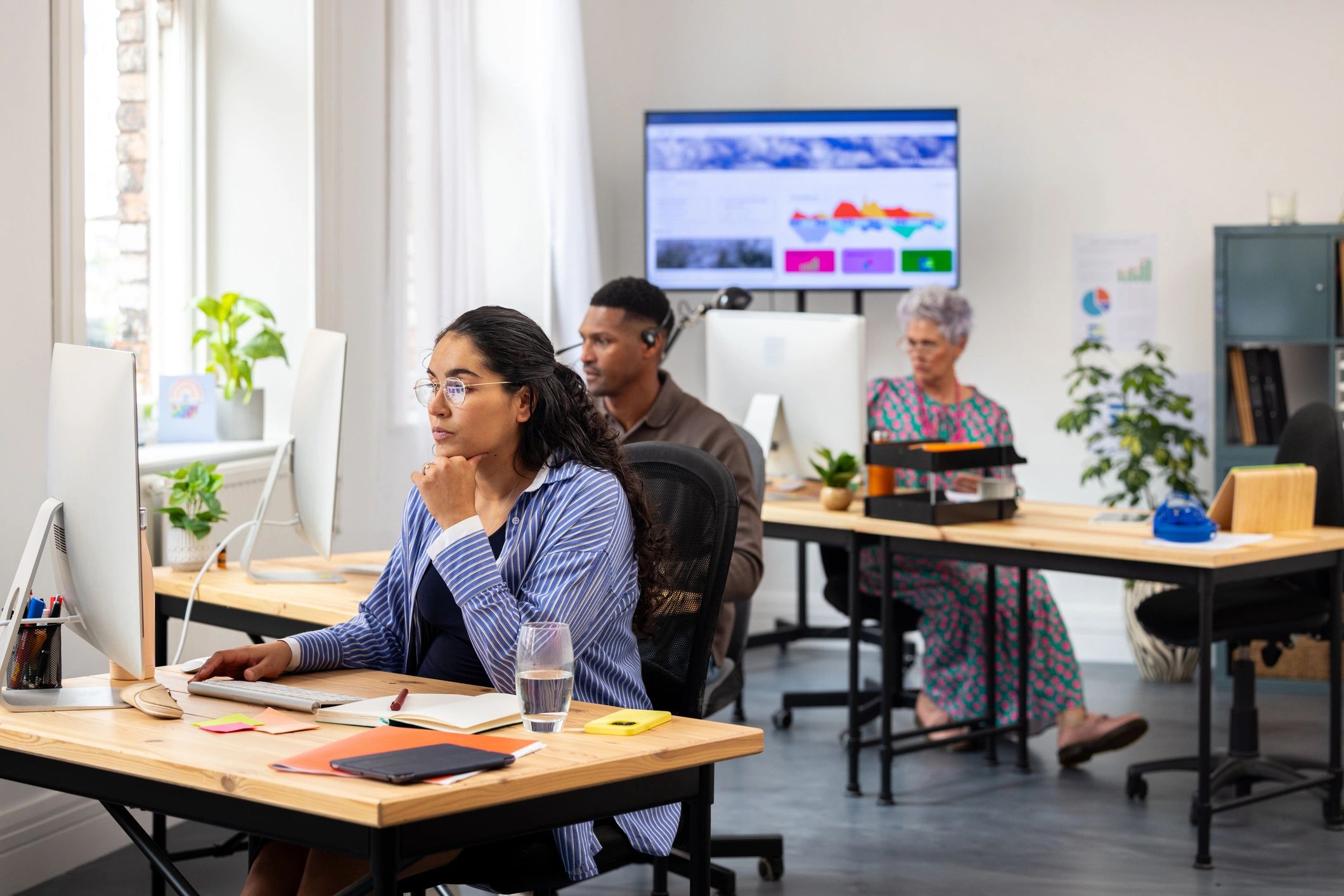 Modern office with team members working and data screen in background